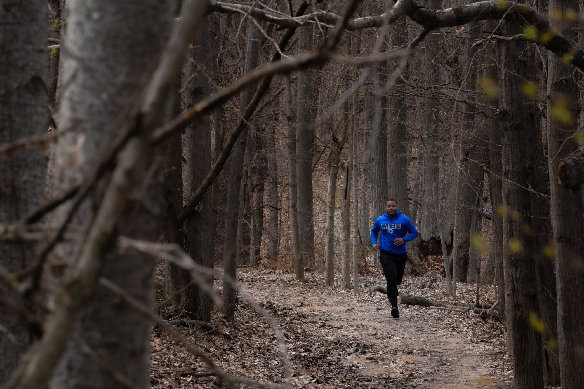 a jogger wearing a gvsu hoodie in the woods
